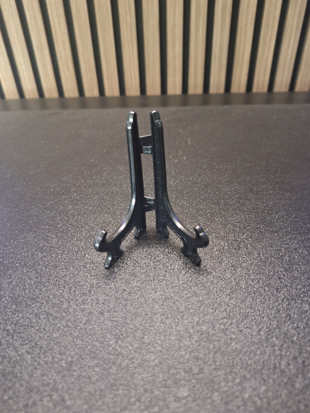 Black 3 inch display stand holding a darts keyring front view
