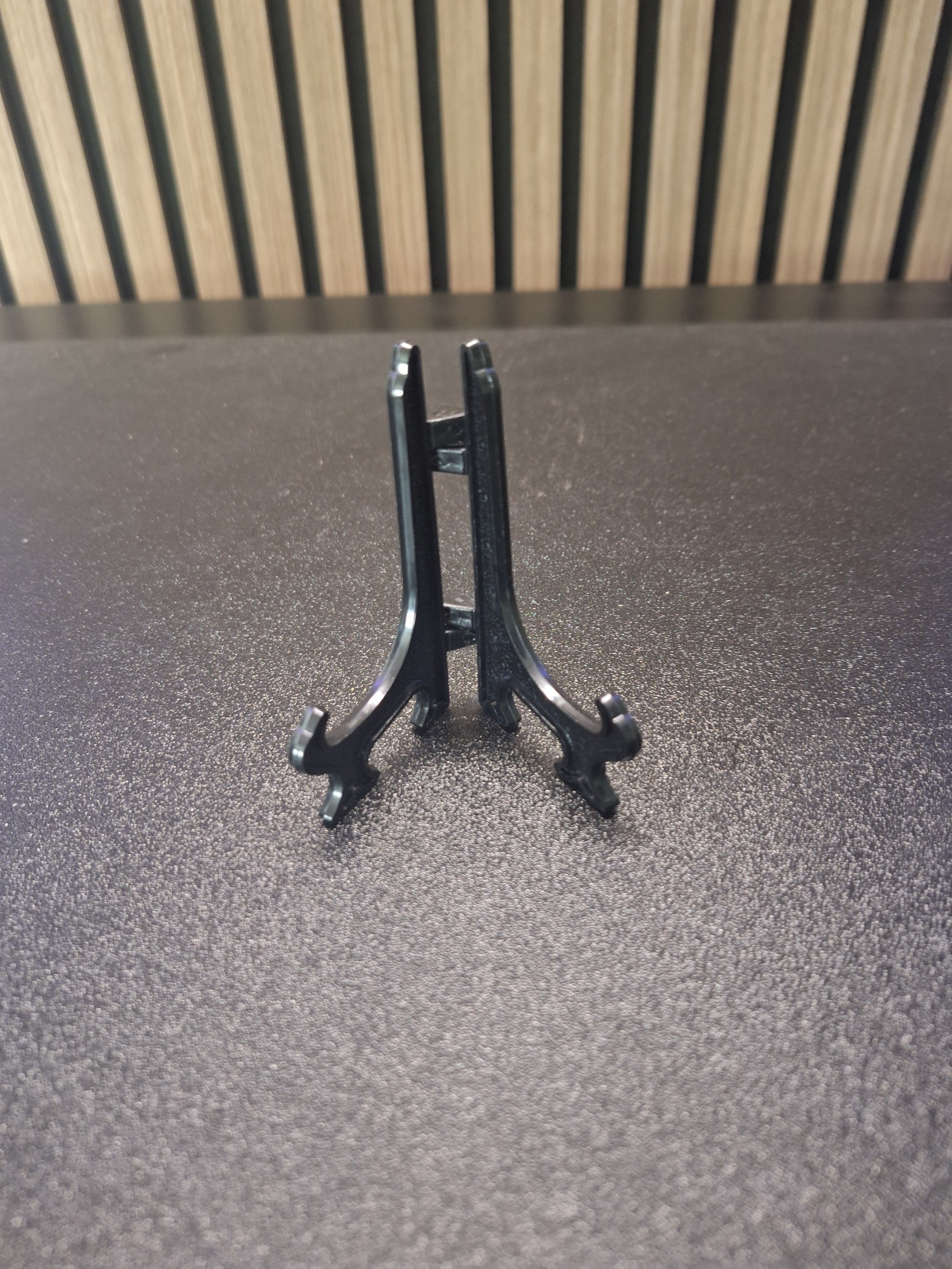 Black 3 inch display stand holding a darts keyring front view