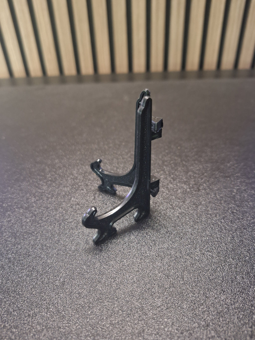 Black 3 inch display stand holding a darts keyring side view